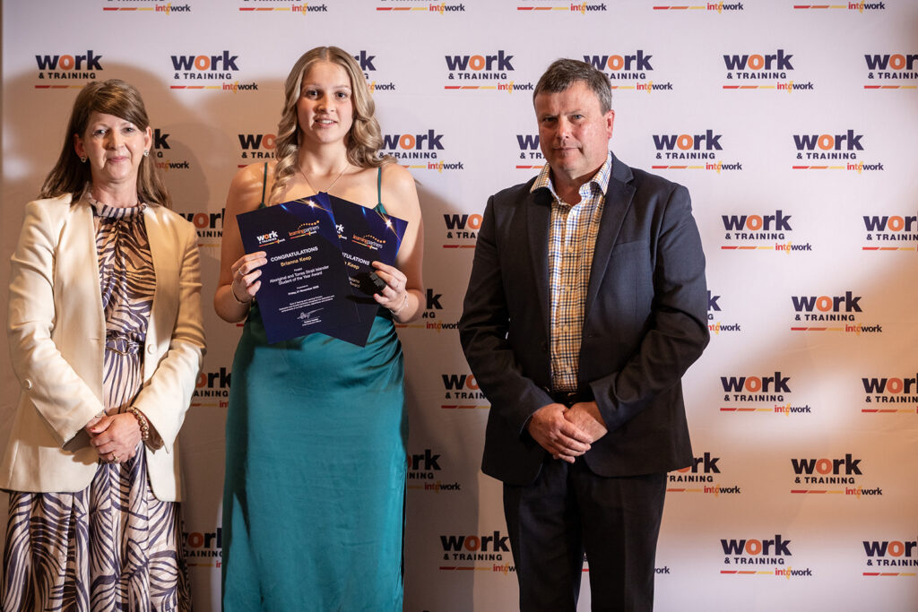 Brianna standing with Work & Training staff holding award certificate