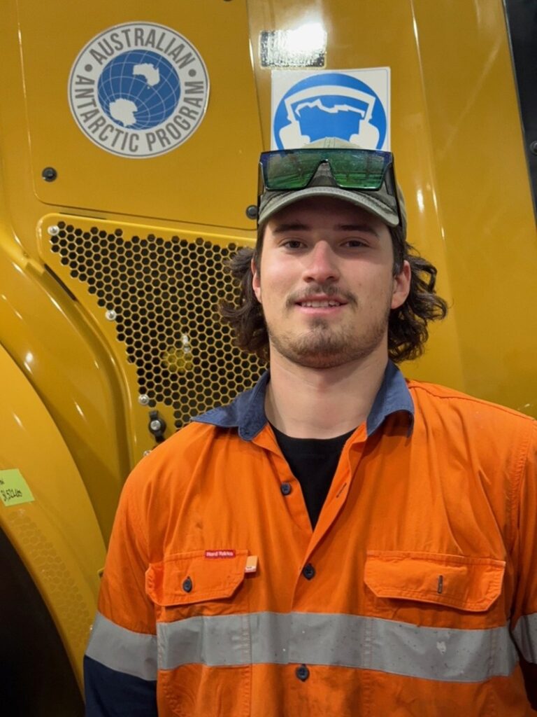 Ky standing infront of heavy machinery at work