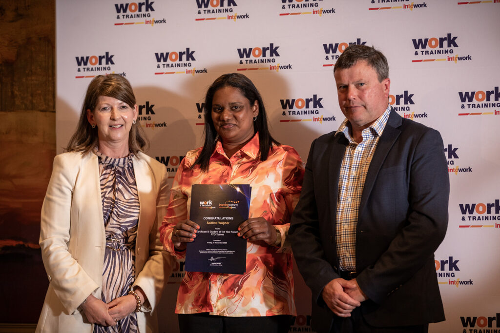 Sahdna standing with Work & Training staff holding award certificate