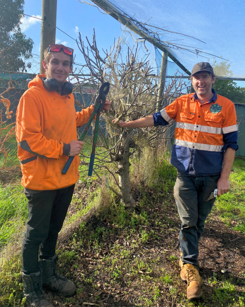 Shane and co worker standing by planted tree.